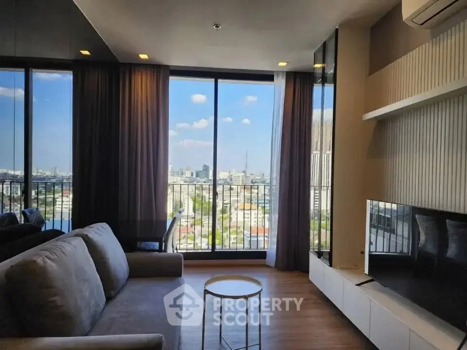 Modern living room with large windows offering stunning city views, featuring a cozy sofa and sleek entertainment unit.