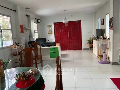Spacious living room with red double doors, modern decor, and ample natural light.