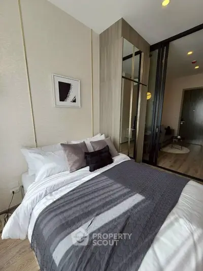 Modern bedroom with stylish decor and large mirror wardrobe in a cozy apartment.