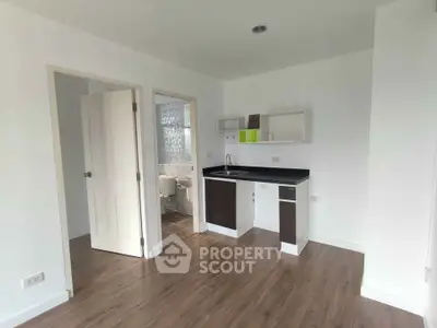 Modern compact kitchen with sleek cabinetry and adjacent bathroom in minimalist apartment