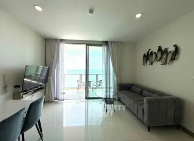Modern living room with ocean view, stylish furniture, and large windows opening to a balcony.