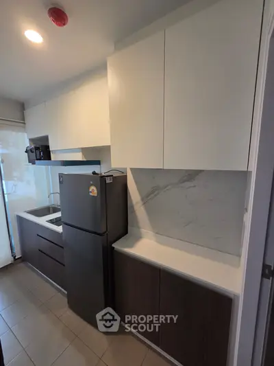 Modern kitchen with sleek cabinetry and stainless steel fridge in a contemporary apartment.