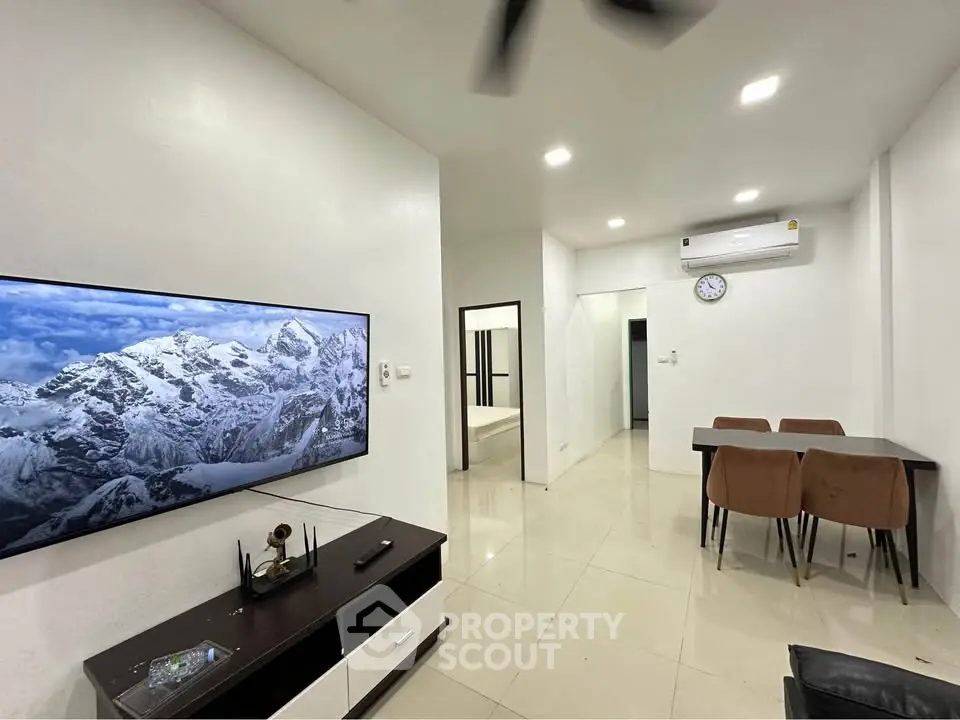 Modern living room with sleek furniture and wall-mounted TV in a bright apartment.