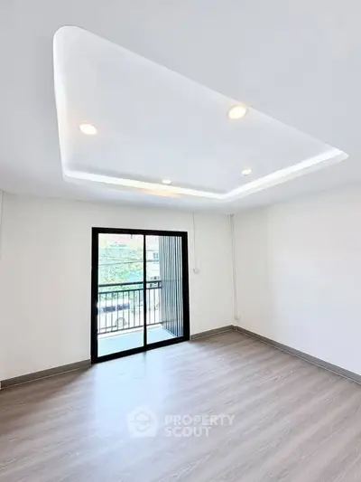Spacious modern living room with sleek ceiling lights and large window balcony access.