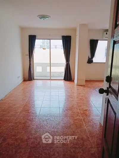 Spacious empty living room with large windows and tiled flooring