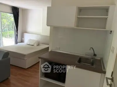 Cozy studio apartment with compact kitchen and garden view, ideal for modern living.