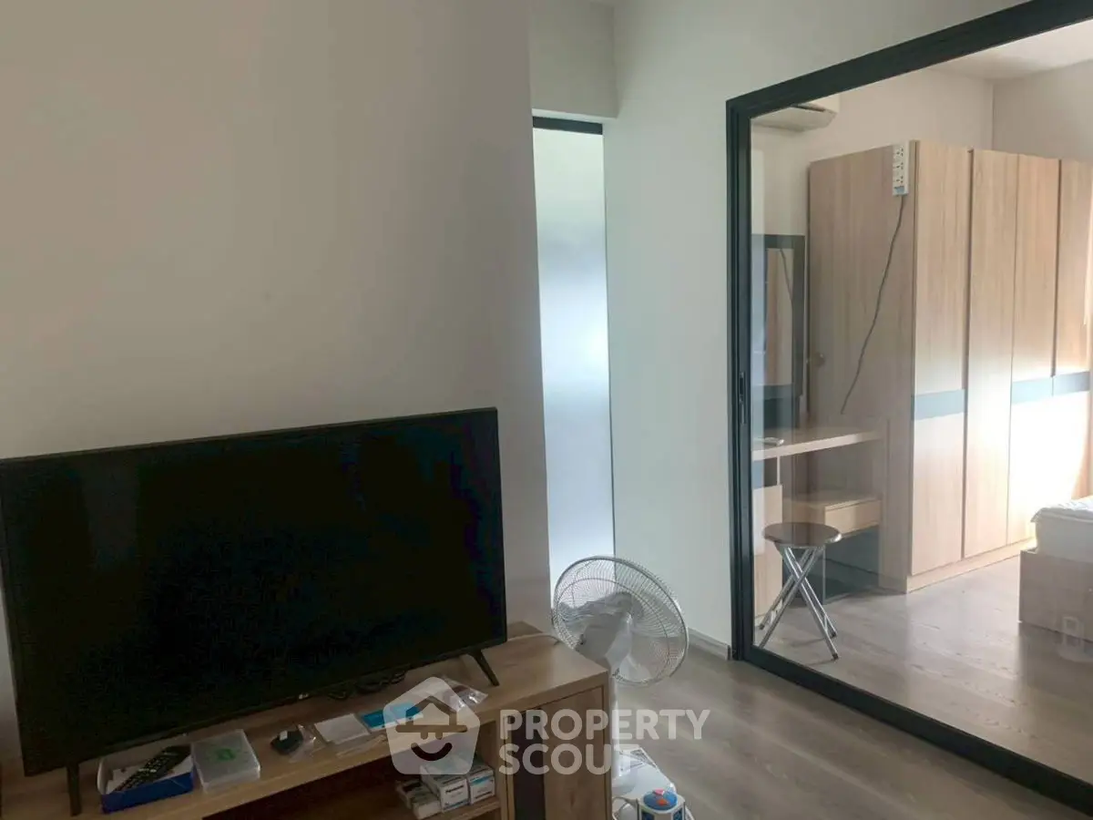 Modern apartment interior with TV and glass partition leading to bedroom