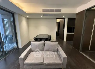 Modern living room with sleek furniture and dining area in open layout apartment.