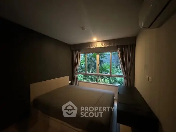 Cozy bedroom with large window and lush garden view, perfect for relaxation.