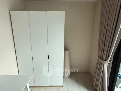 Minimalist bedroom corner with white wardrobe and large window for natural light.