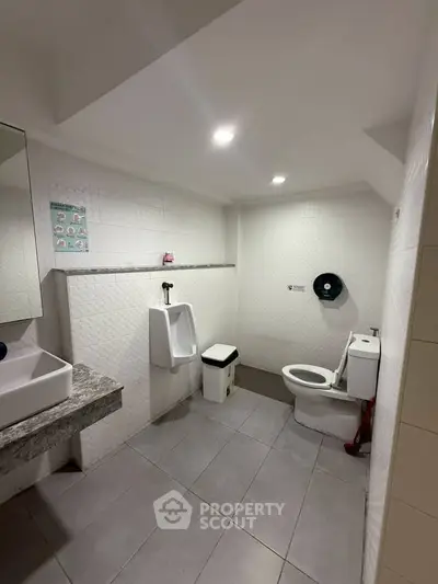 Spacious public restroom with modern fixtures and tiled flooring.