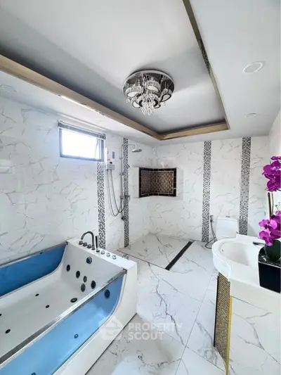 Luxurious bathroom with jacuzzi and elegant chandelier, featuring modern marble design and stylish fixtures.