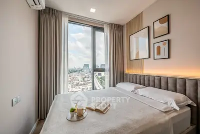 Modern bedroom with large window offering stunning city view, elegant decor, and cozy ambiance.