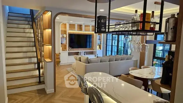 Modern open-plan living room with stylish decor and elegant staircase