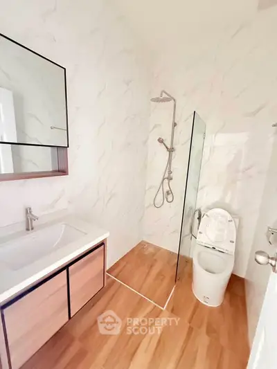 Modern bathroom with sleek fixtures and glass shower partition in a stylish real estate property.
