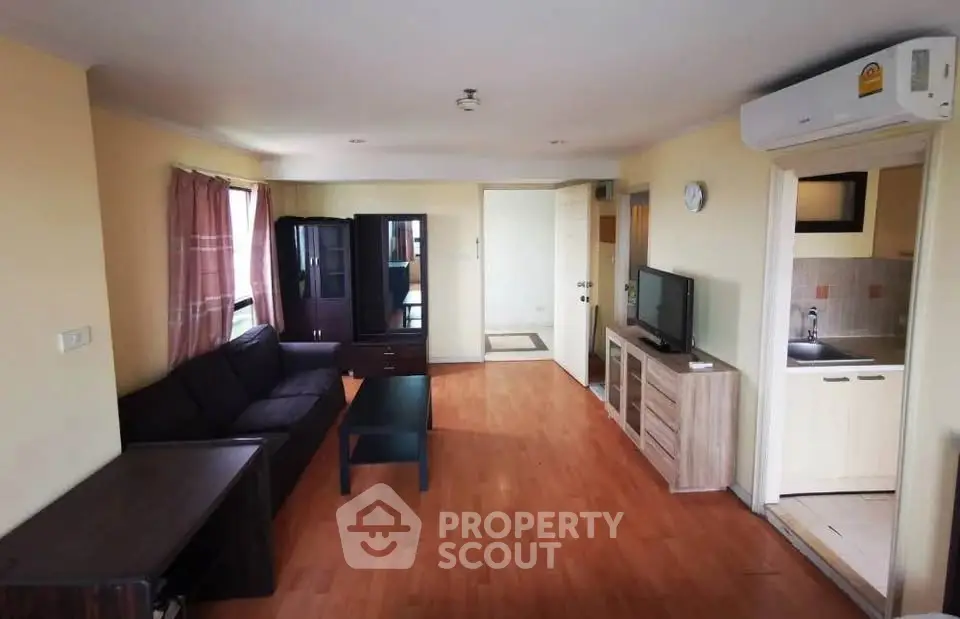 Spacious living room with modern furniture and open kitchen layout in a cozy apartment.