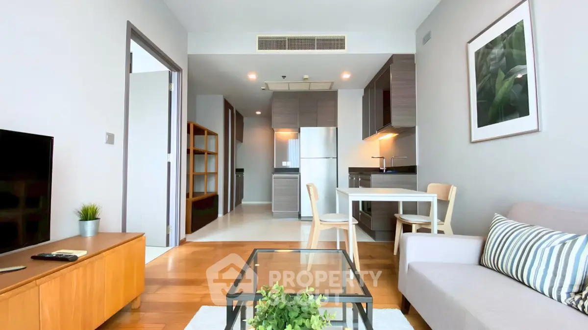 Modern living room with open kitchen, stylish furniture, and natural light.