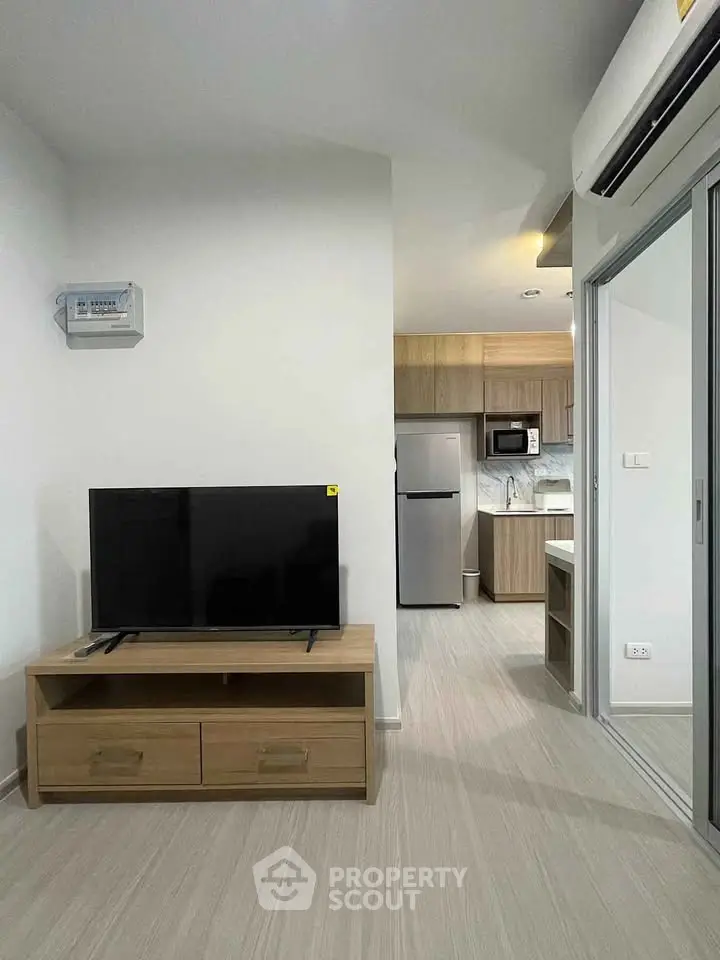 Modern apartment interior with sleek kitchen and cozy living area featuring a flat-screen TV and air conditioning.