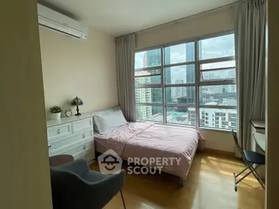 Cozy bedroom with city view, featuring large windows and stylish furnishings.