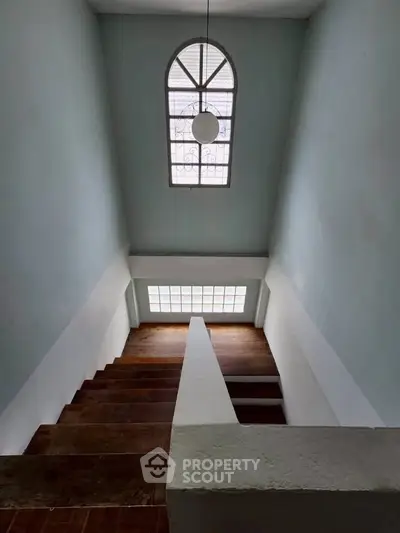 Elegant staircase with arched window and modern lighting in a spacious home