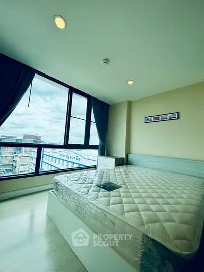 Spacious bedroom with large window offering city views and natural light.