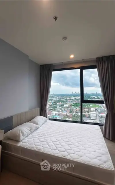 Spacious bedroom with panoramic city view from large window in modern apartment.