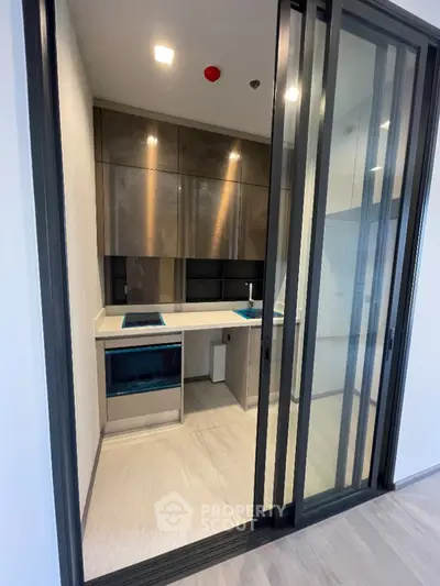 Modern compact kitchen with sleek sliding glass doors and contemporary design
