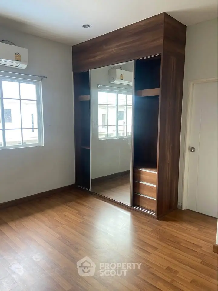 Spacious bedroom with wooden flooring and built-in wardrobe