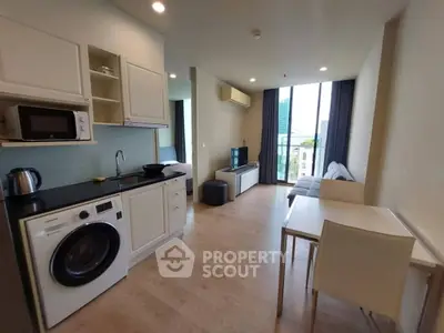 Modern open-layout living room with kitchen, featuring sleek appliances and a cozy seating area with city view.