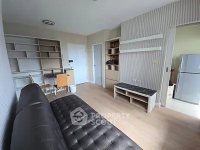 Modern living room with stylish furniture and built-in shelves, featuring a sleek black sofa and wooden flooring.