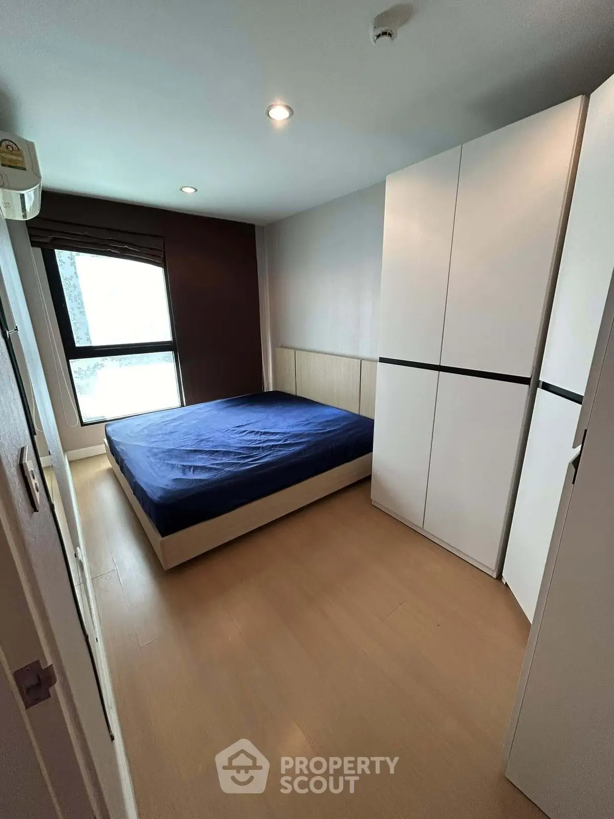 Cozy bedroom with modern wardrobe and natural light in a stylish apartment.