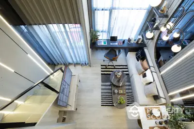 Modern loft-style living room with high ceilings, stylish decor, and large windows for natural light.