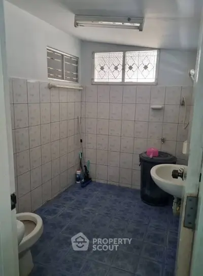 Spacious bathroom with tiled walls and floor, featuring essential fixtures and natural light.