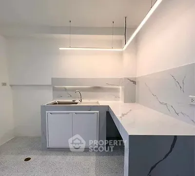 Modern minimalist kitchen with sleek marble countertops and integrated sink