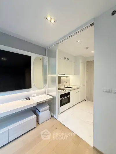 Modern compact kitchen with sleek white cabinetry and integrated appliances in a stylish apartment.