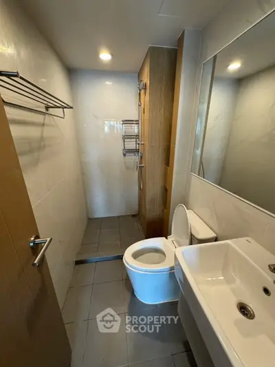 Modern bathroom with sleek fixtures and spacious shower area in contemporary apartment.