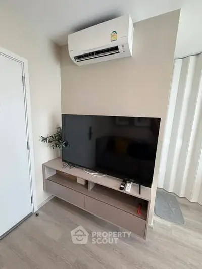 Modern living room with sleek TV setup and air conditioning unit.