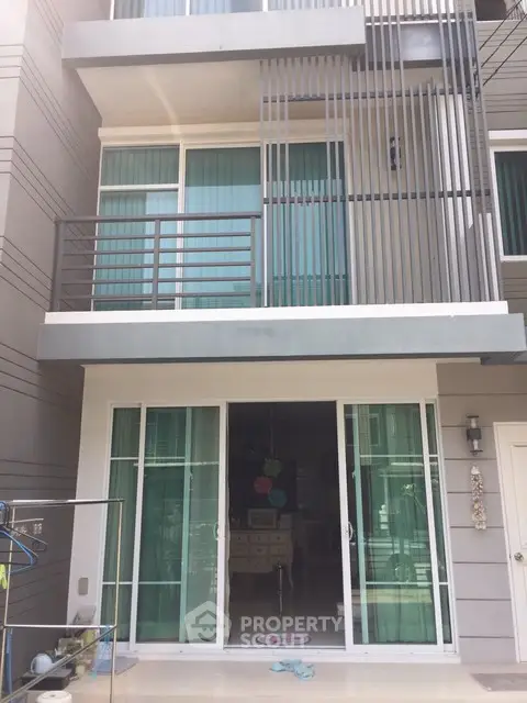 Modern townhouse exterior with sliding glass doors and balcony