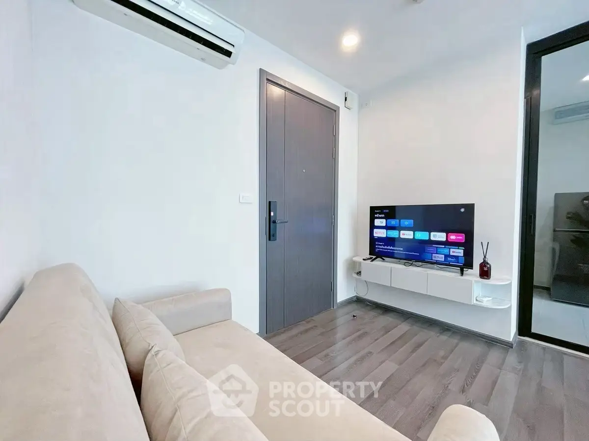 Modern living room with sleek TV setup and cozy beige sofa, perfect for relaxation.