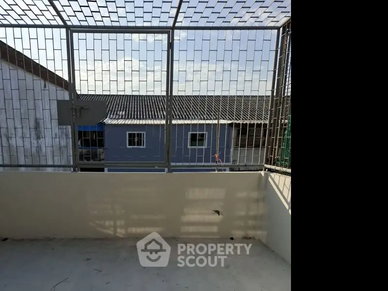 Spacious balcony with metal railing offering a view of neighboring buildings.