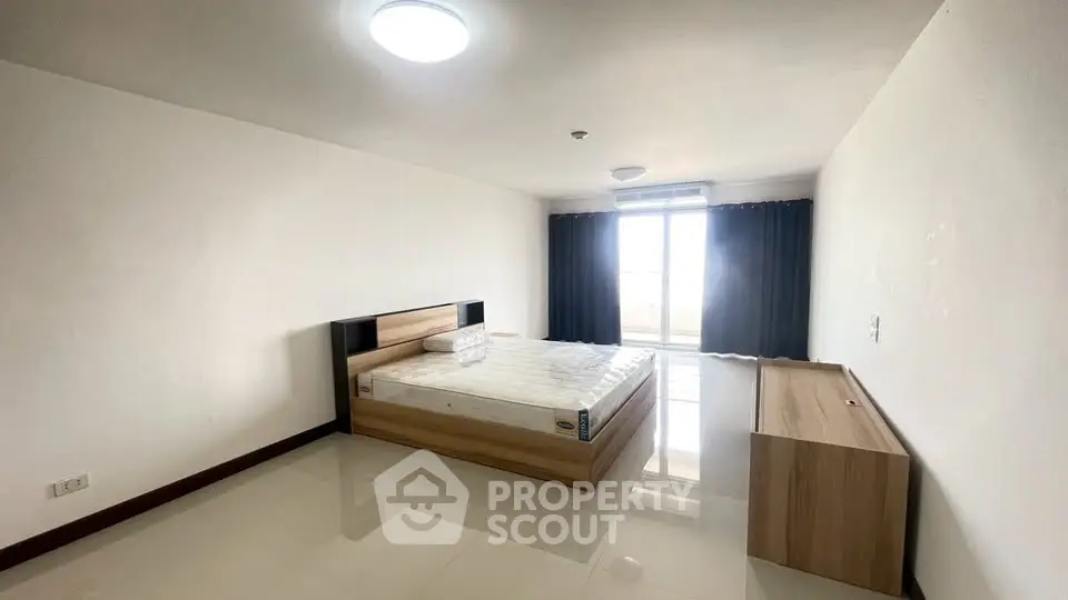 Spacious bedroom with modern furnishings and large window for natural light.