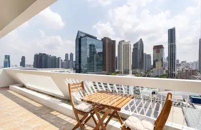Stunning city view from a spacious balcony with modern seating, perfect for relaxation and entertainment.
