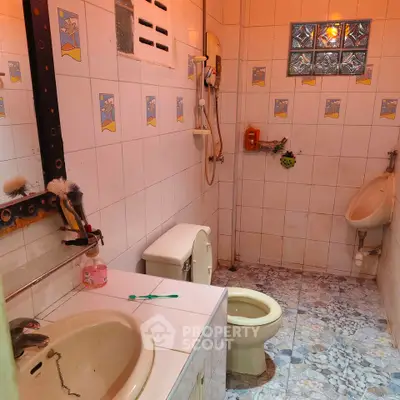Cozy bathroom with tiled walls and essential fixtures, ideal for compact living spaces.