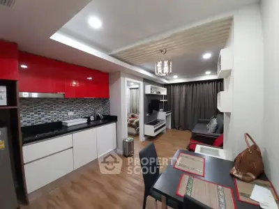Modern open-layout kitchen and living room with stylish red cabinets and cozy dining area.