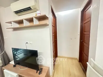 Modern apartment interior with TV, air conditioning, and wooden doors in a cozy hallway.