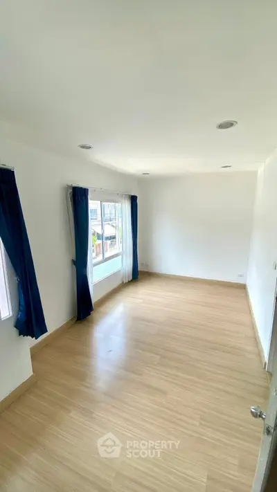 Spacious empty room with large windows and wooden flooring, perfect for customization.