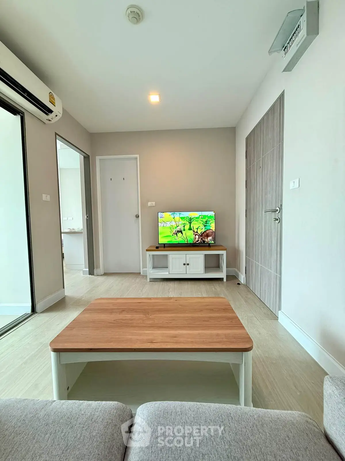 Modern living room with sleek furniture and TV, featuring a cozy ambiance and neutral tones.