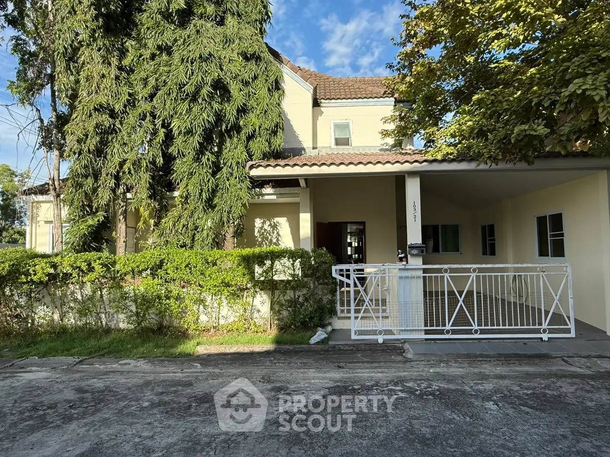Charming two-story house with lush greenery and gated driveway