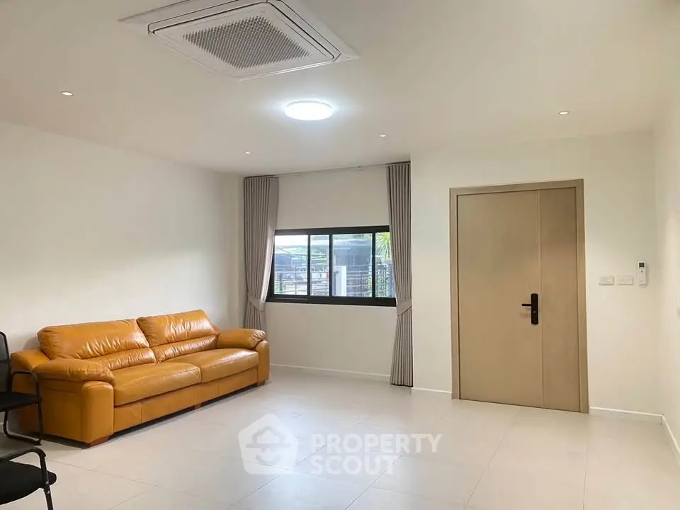 Spacious living room with modern leather sofa and large window