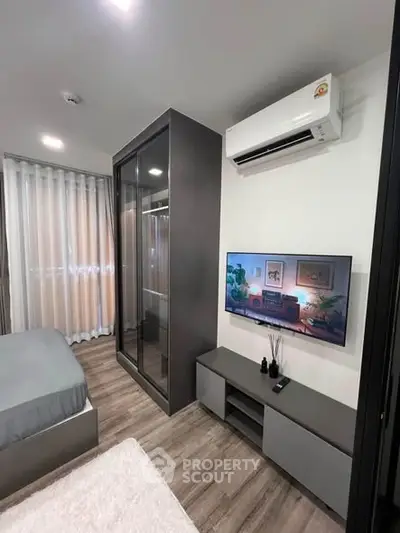 Modern bedroom with sleek design, featuring a wall-mounted TV, air conditioning, and stylish furniture.